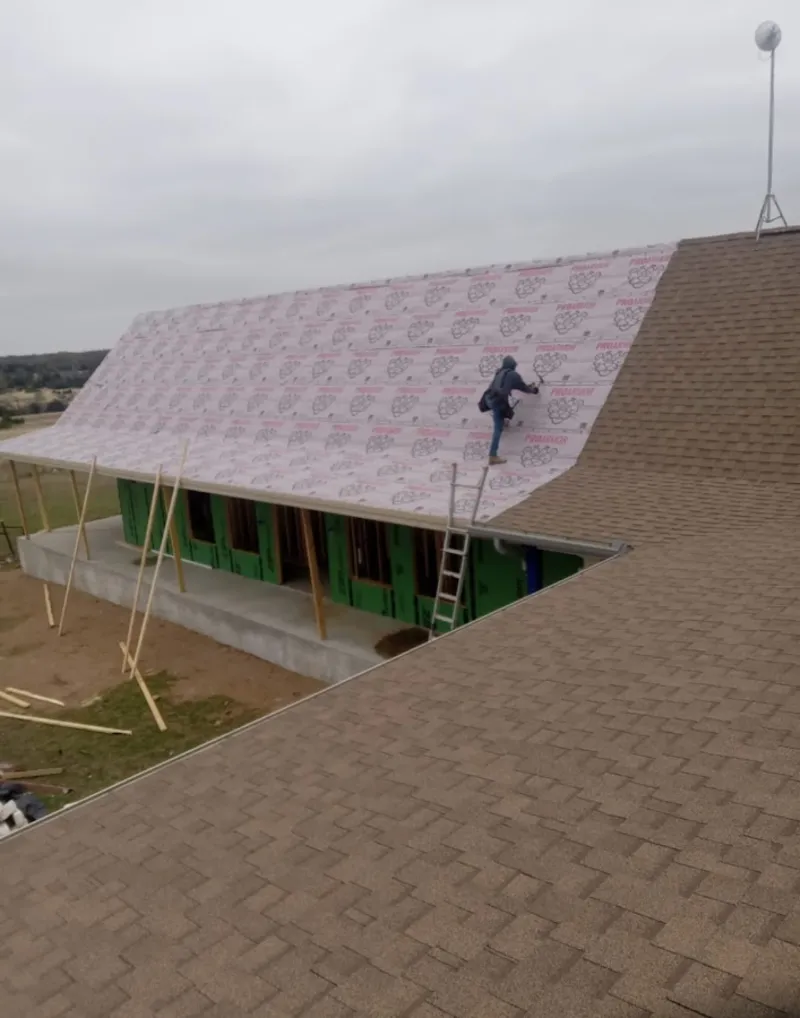 Worker preparing underlayment for a metal roof installation in Creston